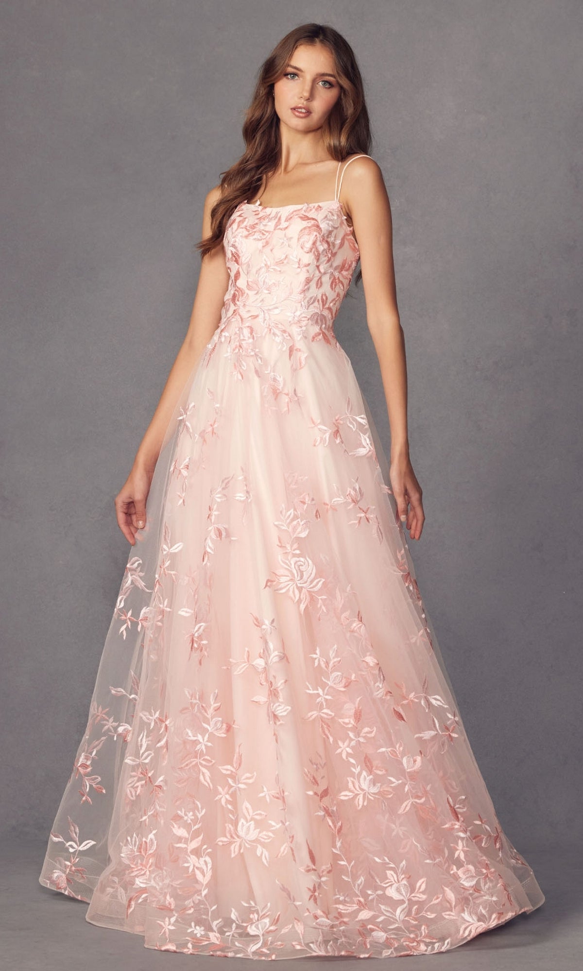A woman wearing the Embroidered-Lace Long A-Line Prom Ball Gown 279, featuring thin straps and a floor-length design, stands against a plain gray background.